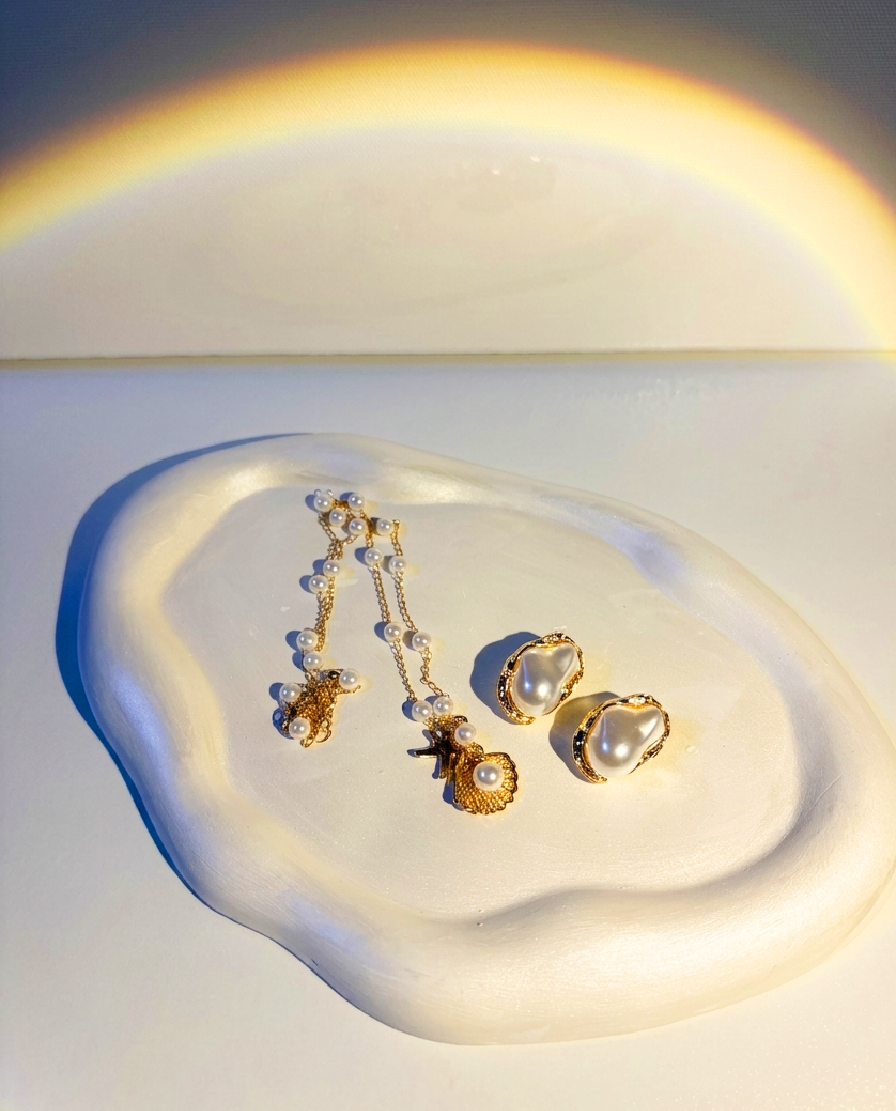 Minimalist white RocioTreasure tray styled with pearl jewelry under warm sunlight.